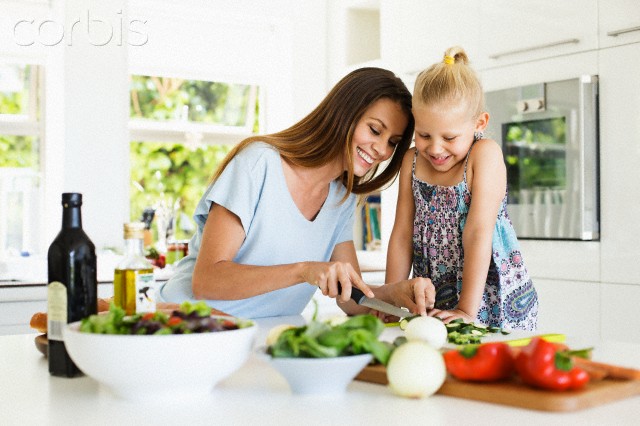 Mother and daughter (4-5) preparing food in kitchen